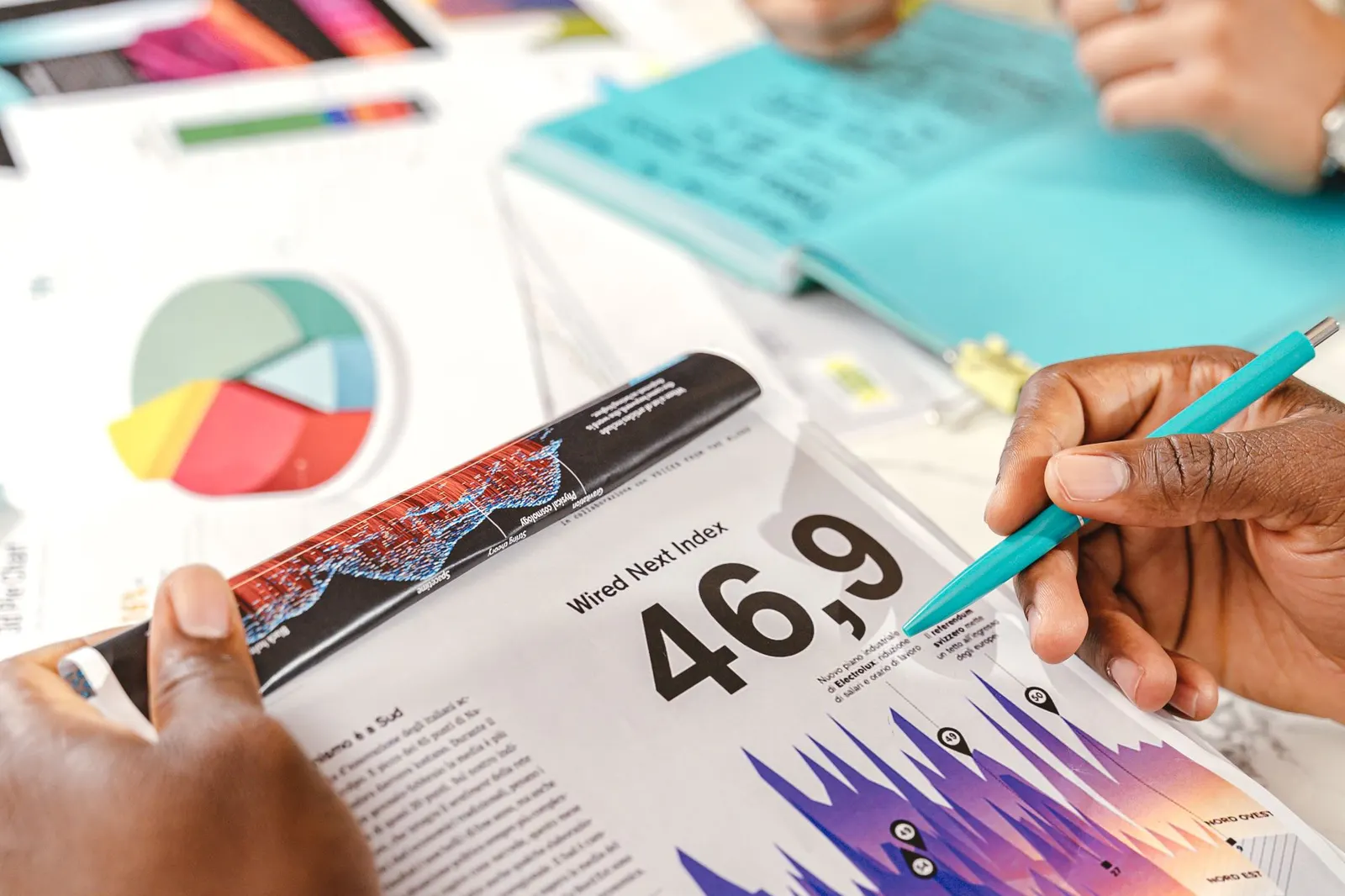Hands holding a printed analytics report with a pie chart and colorful bar graphs while marking it with a pen